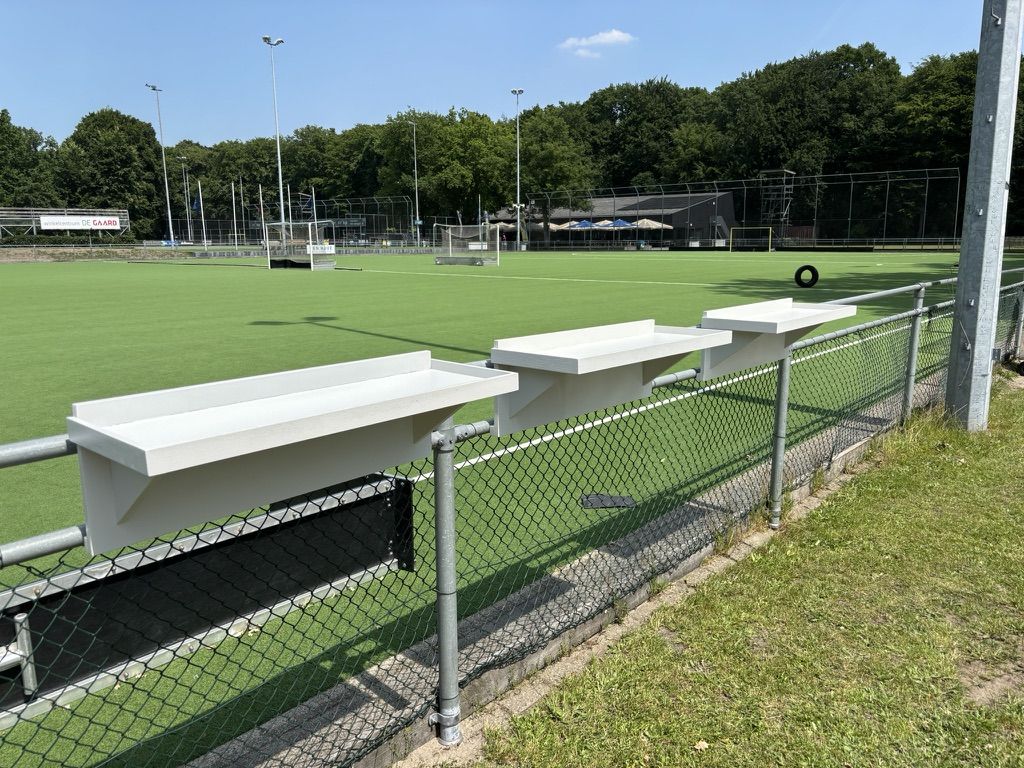 Veldbarren aan het hek, schuin gezien, met het veld op de achtergrond