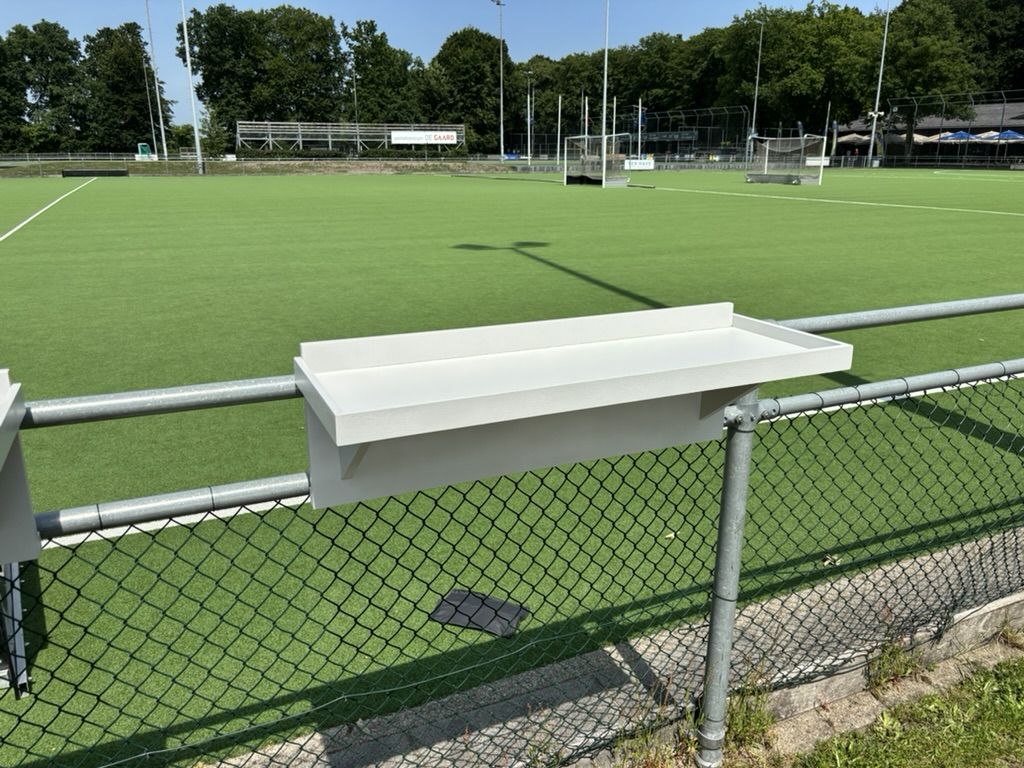 Losse Veldbar aan het hek met het groene kunstgrasveld erachter