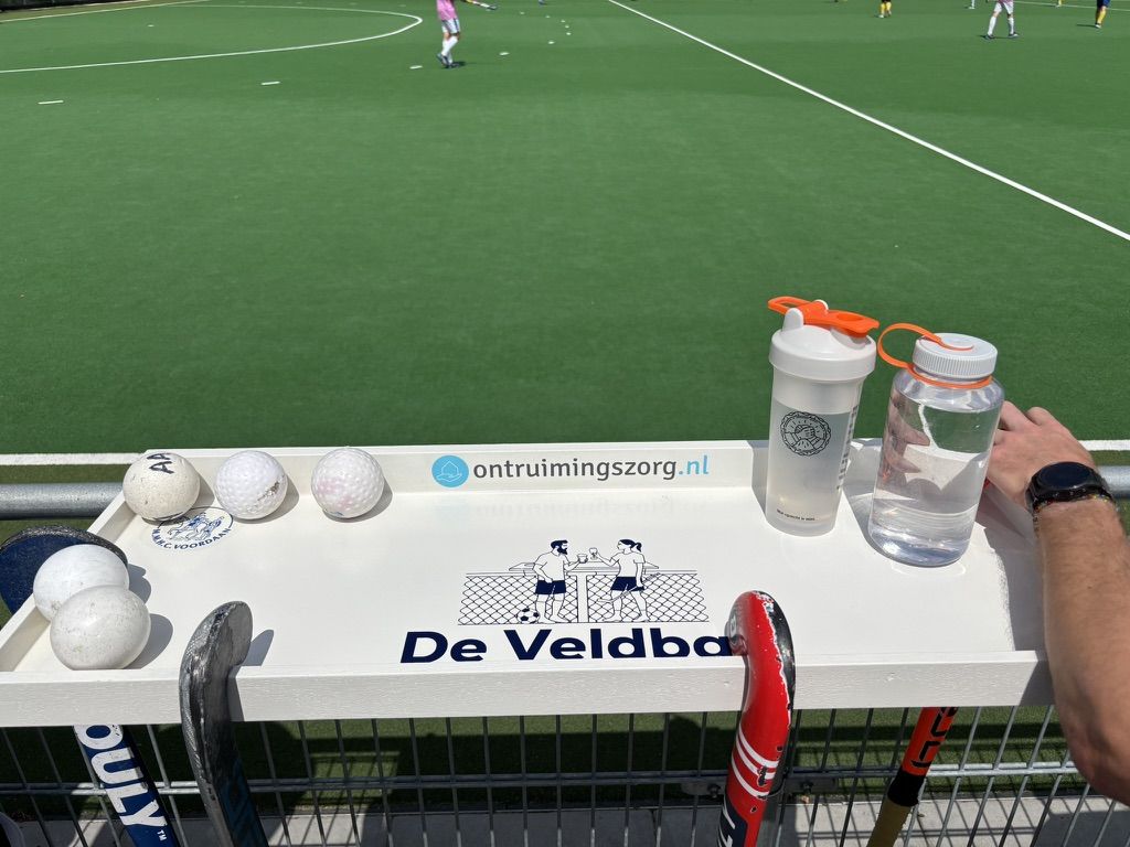 Bovenkant van De Veldbar met het clublogo van MMHC Voordaan, het logo van De Veldbar en een sponsorlogo